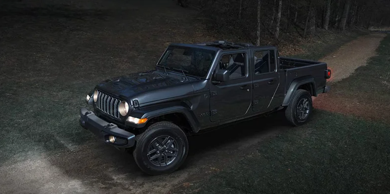 A black Jeep Gladiator parked on a dirt road.