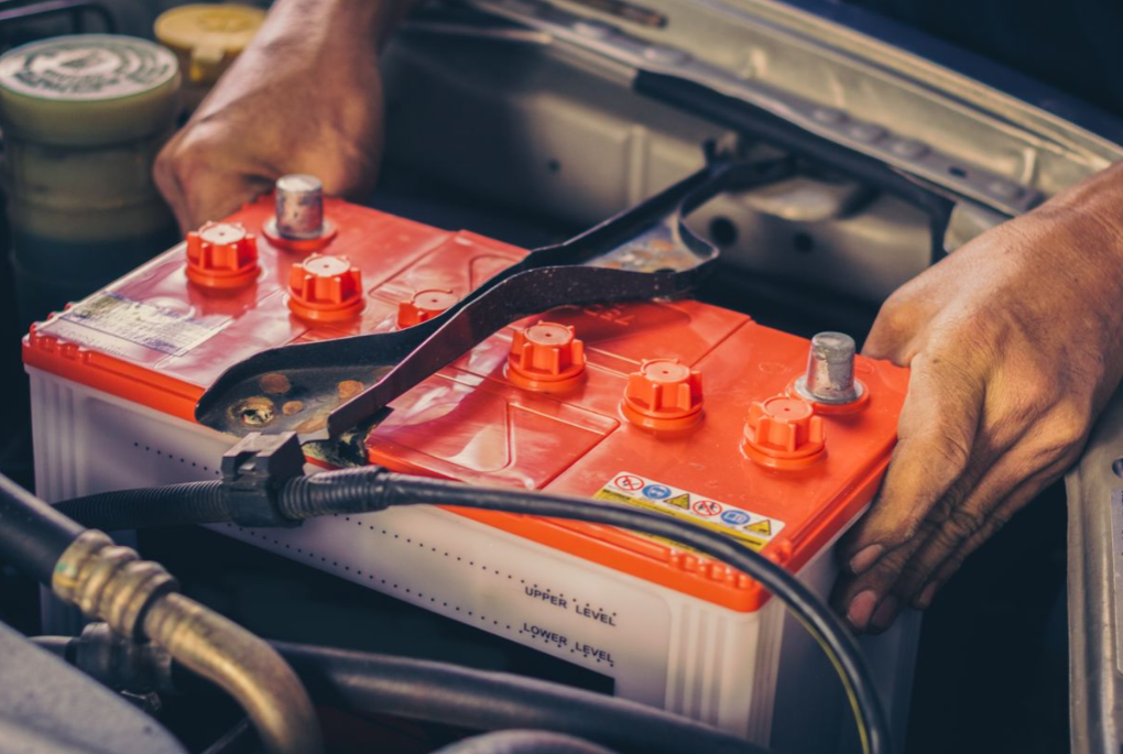A person installing a new car battery.