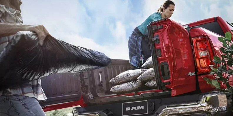 Two people loading bags in to the back of a 2026 RAM 1500.